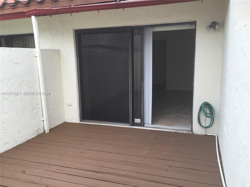 A wooden deck sits outside a sliding glass door leading into a residential interior — 331 Ives Dairy Rd # 10, Miami FL 33179, MIAMI, FL