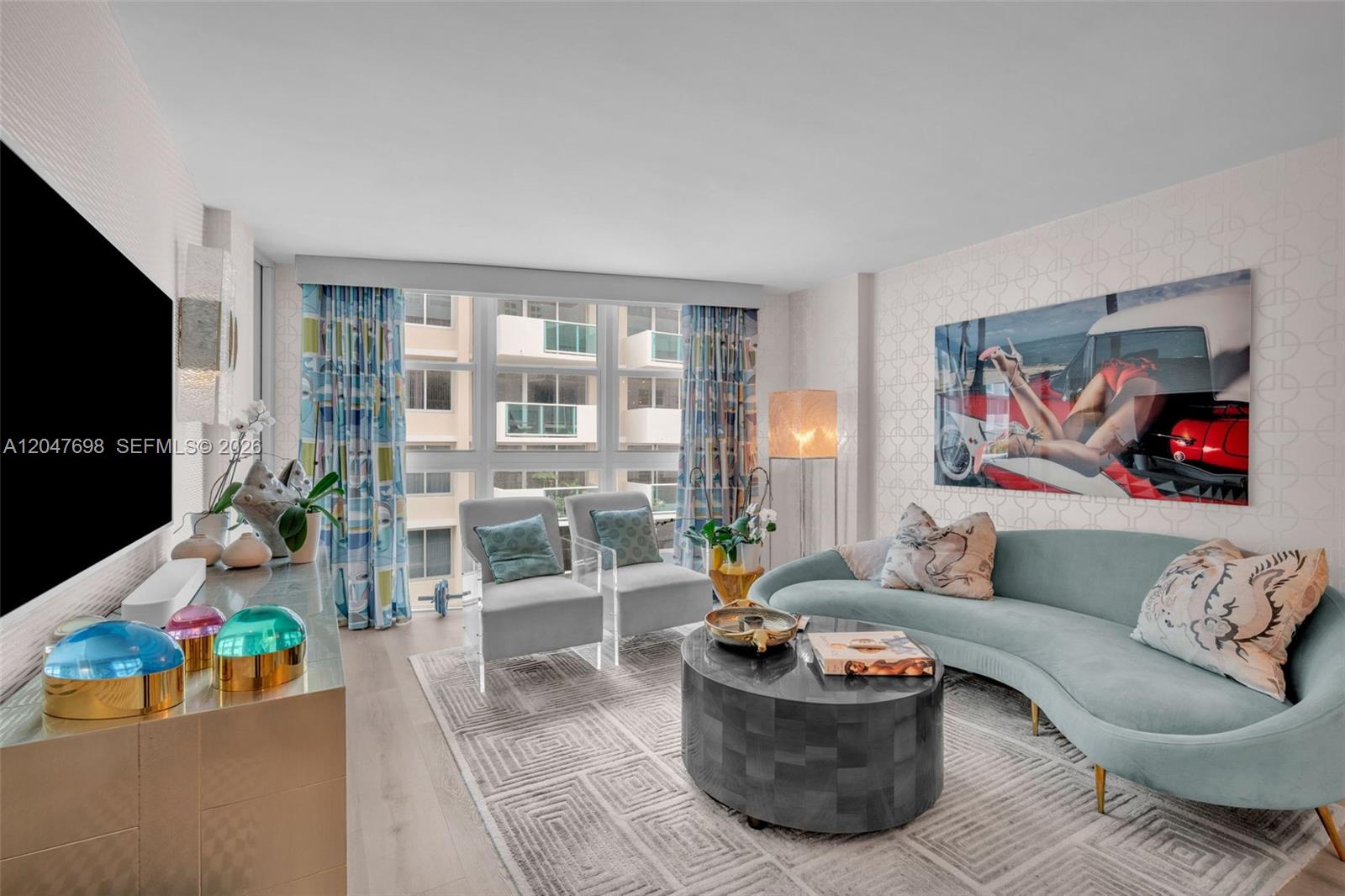 A living room features a curved light blue sofa, two acrylic chairs, and patterned wallpaper — 1228 West Ave # 1213, Miami Beach FL 33139, MIAMI BEACH, FL