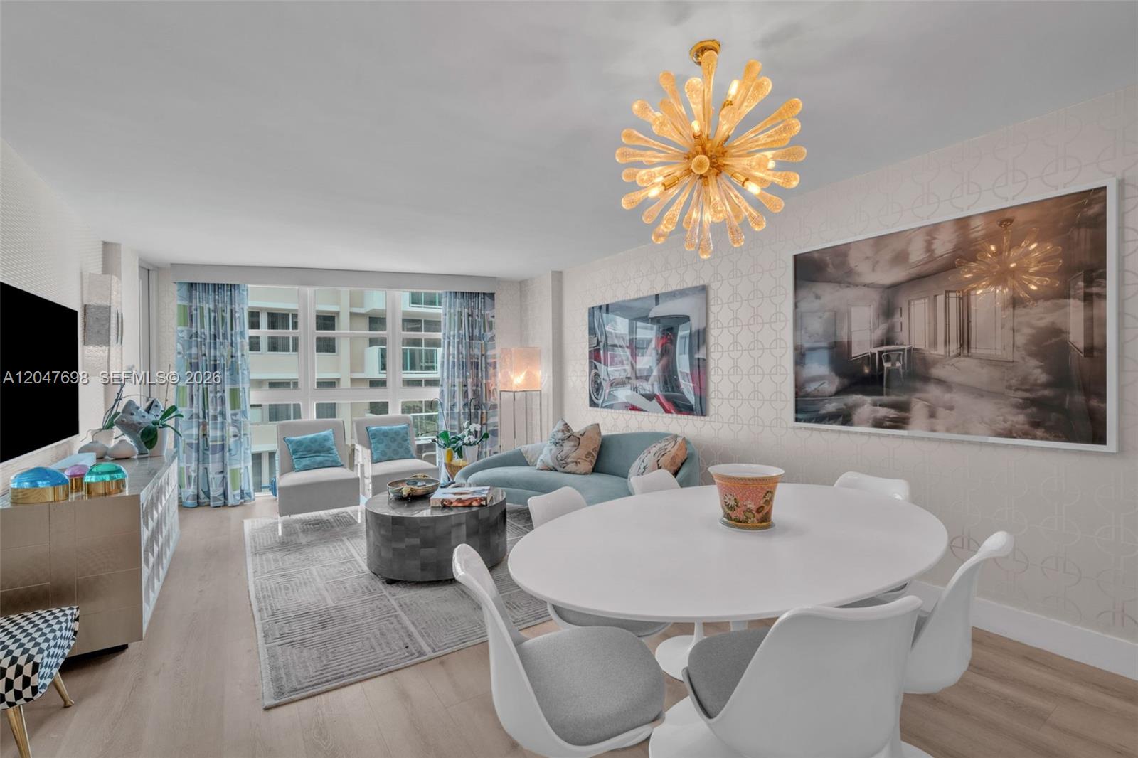 A living and dining room features a starburst chandelier, white oval table, and blue sofa — 1228 West Ave # 1213, Miami Beach FL 33139, MIAMI BEACH, FL