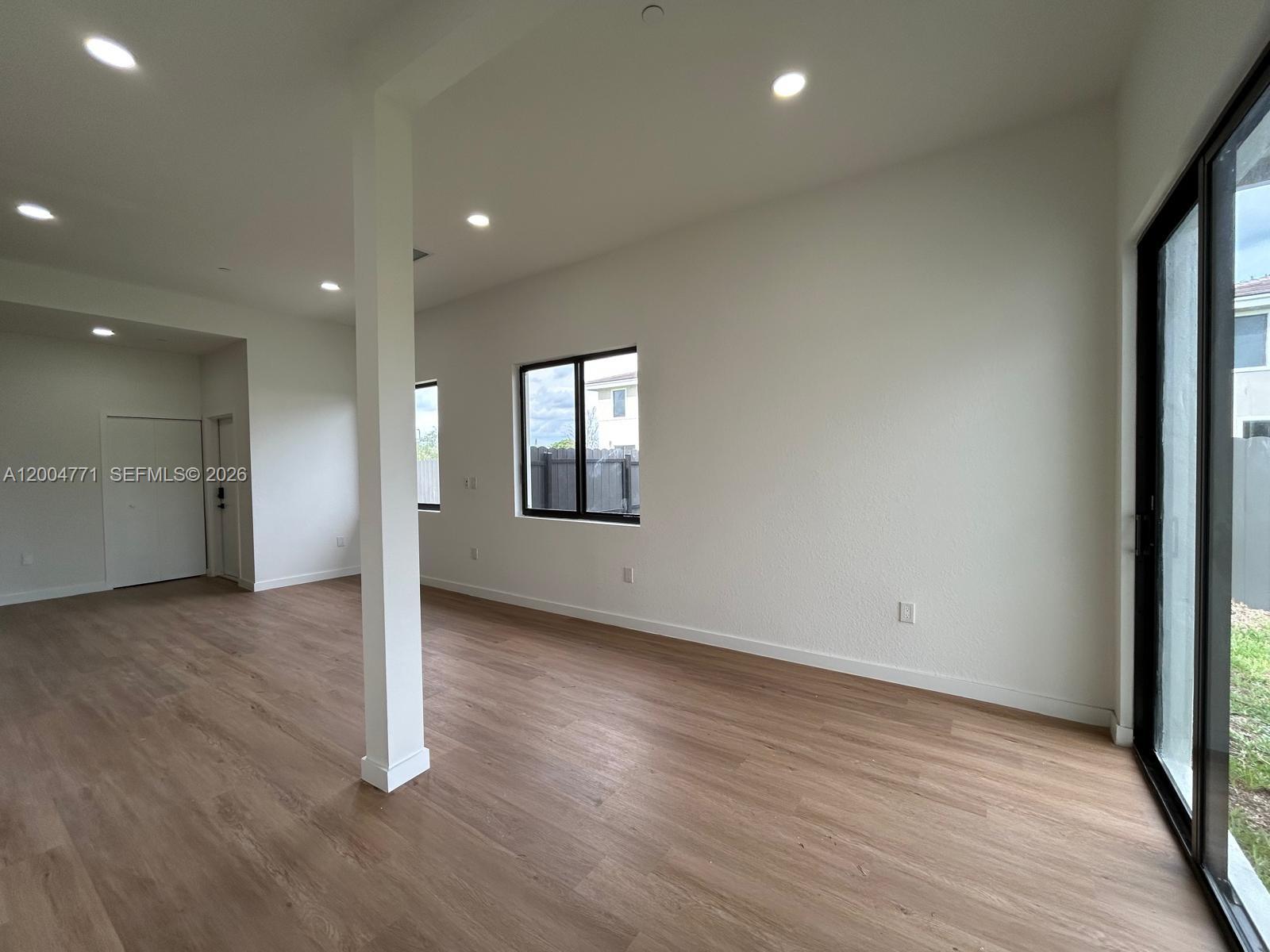 An empty bedroom features light-colored walls, a single window with blinds, and wood-look flooring — 19428 SW 125th AVE # 0, Miami FL 33177, MIAMI, FL