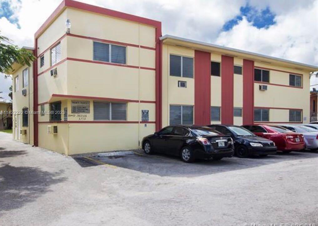 A two-story apartment building with yellow stucco walls and red trim features a parking lot — 71 NW 76th St # 16, Miami FL 33150, MIAMI, FL