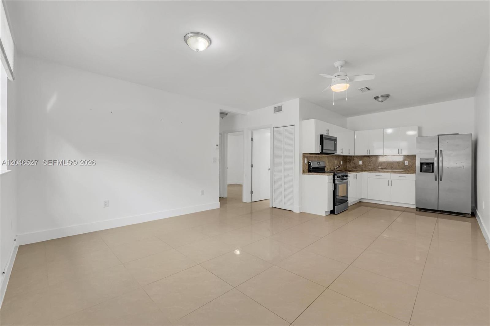 An open-concept living area features white walls, beige tile flooring, and a modern kitchen — 7537 NW 3rd Ave # 2, Miami FL 33150, MIAMI, FL
