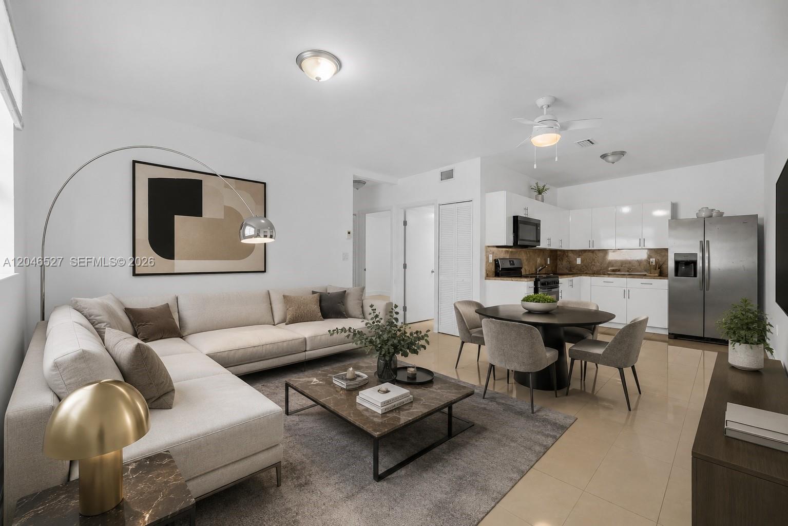 A modern open-concept living and dining area features a sectional sofa, kitchen, and tile flooring — 7537 NW 3rd Ave # 2, Miami FL 33150, MIAMI, FL