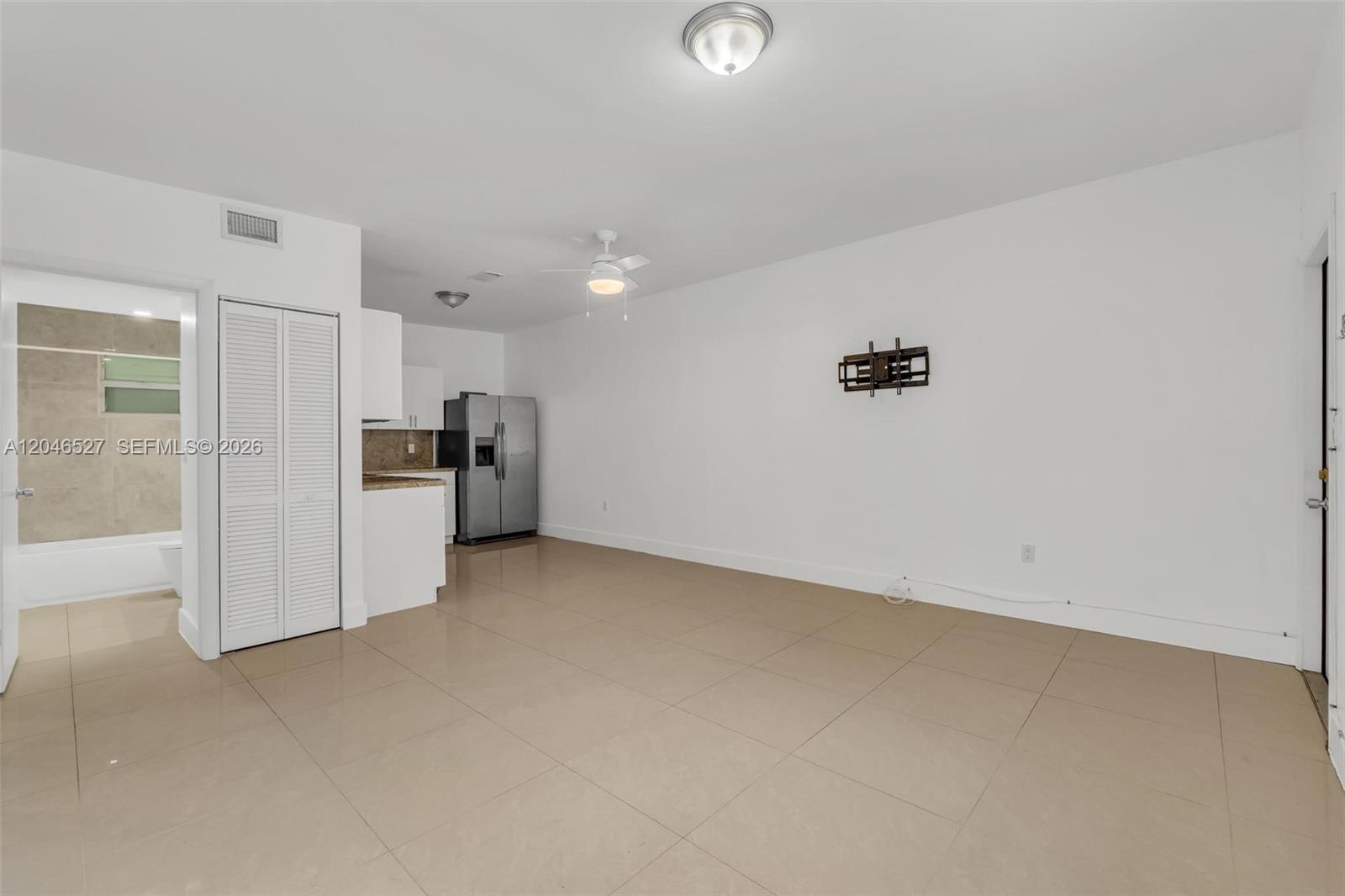 An open-plan living area features light tile flooring, a ceiling fan, and an adjacent kitchen — 7537 NW 3rd Ave # 2, Miami FL 33150, MIAMI, FL