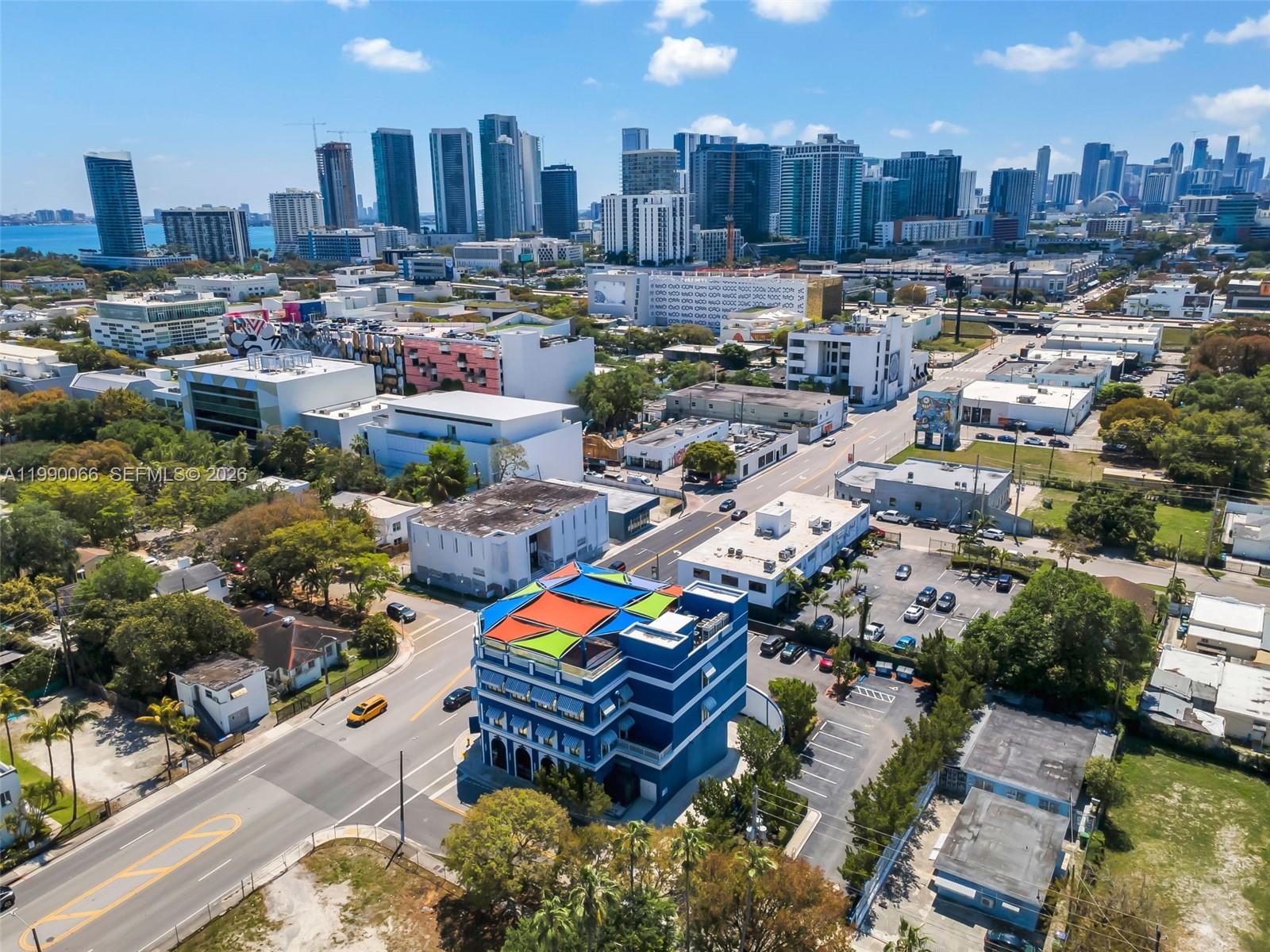 An aerial view shows a blue building with colorful roof sails in a city neighborhood — 4136 N Miami Ave, Miami FL 33127, MIAMI, FL