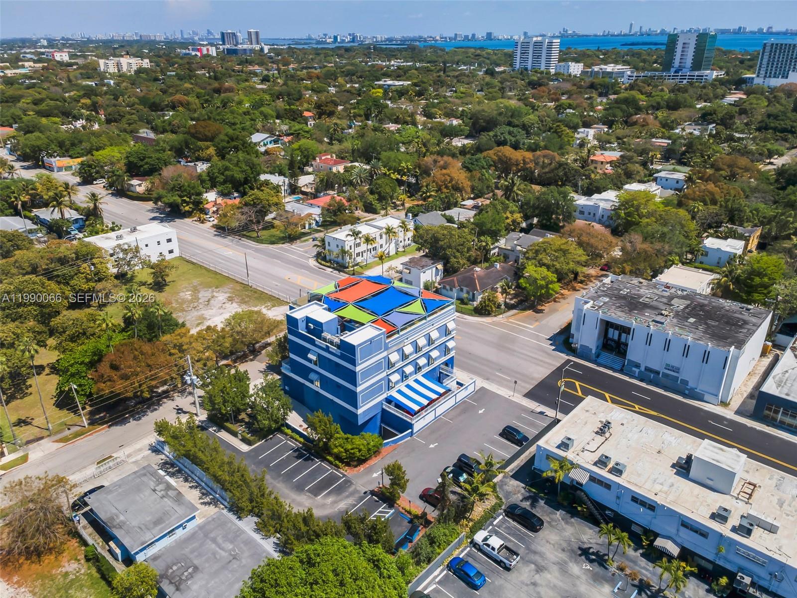 An aerial view shows a blue multi-story building with a colorful rooftop shade structure — 4136 N Miami Ave, Miami FL 33127, MIAMI, FL