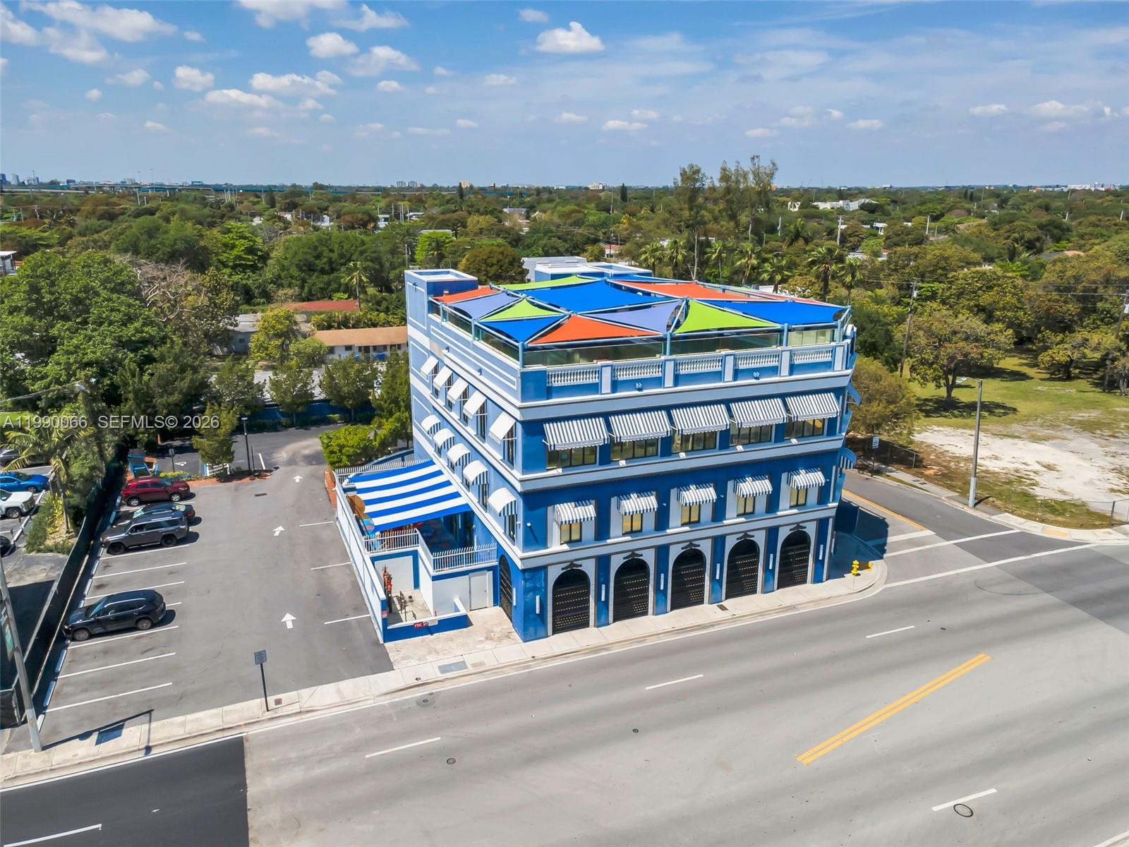 An aerial view shows a blue multi-story commercial building with a rooftop terrace and awnings — 4136 N Miami Ave, Miami FL 33127, MIAMI, FL