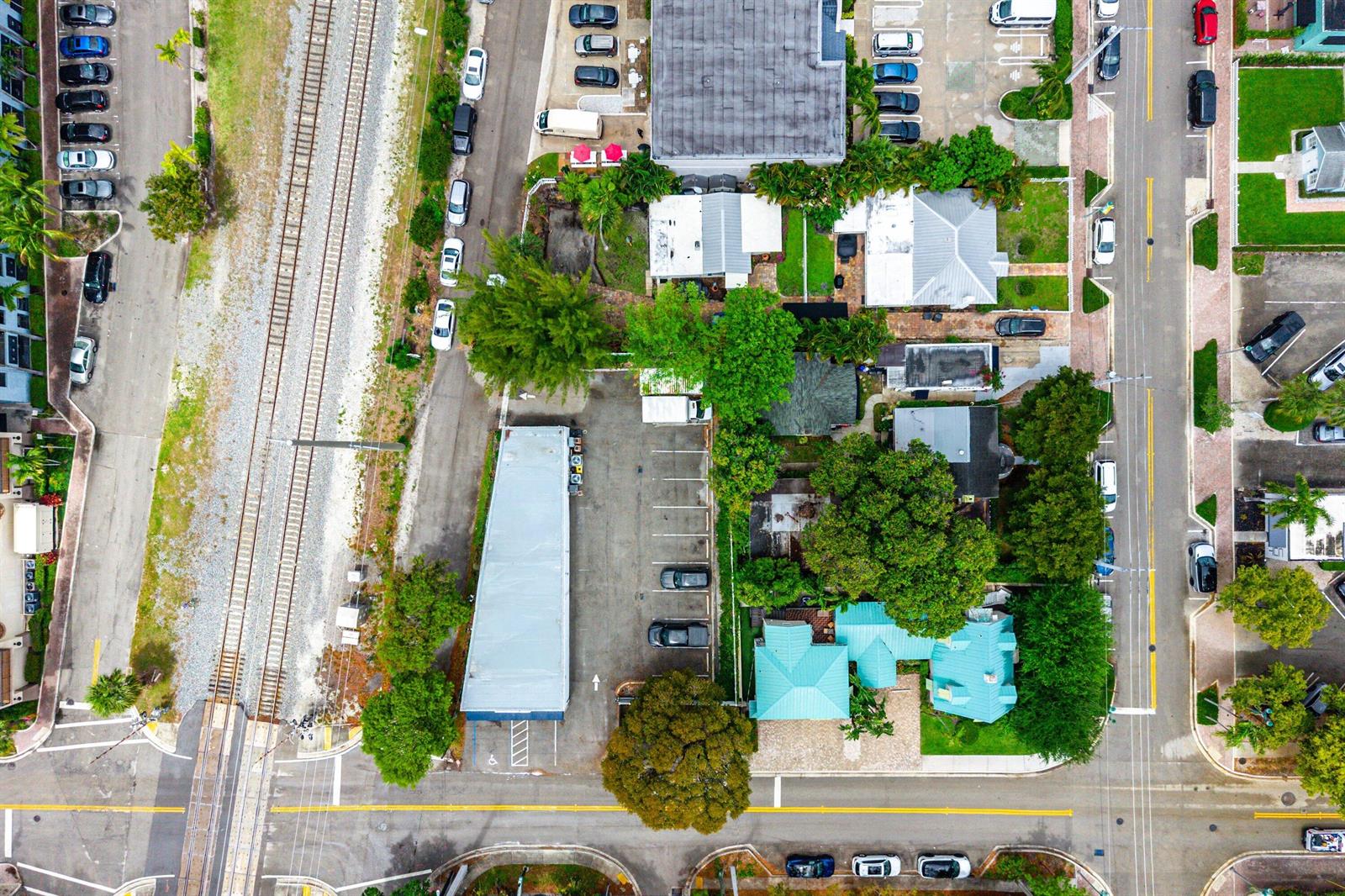 An aerial view shows a parking lot, a long building, and residential houses near tracks — 301 NE 1st Street, Delray Beach FL 33483, DELRAY BEACH, FL