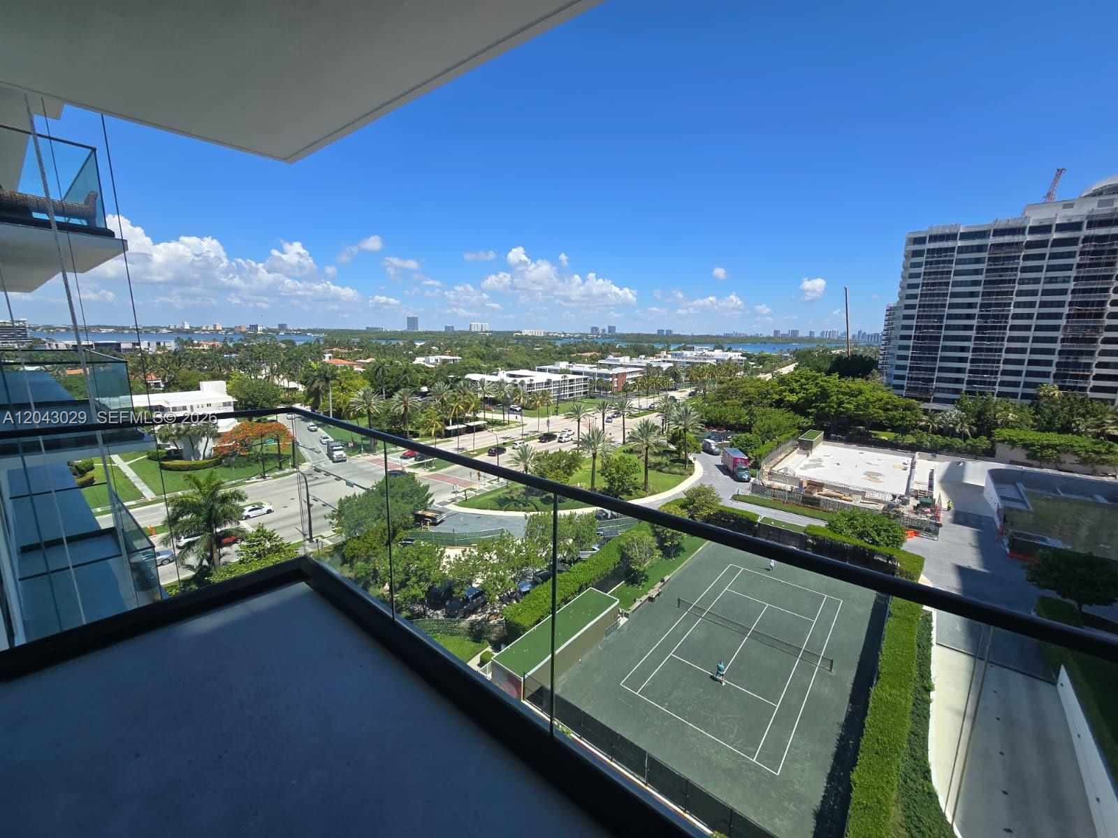 A high-angle view from a balcony overlooking a tennis court, street, and city skyline — BAL HARBOUR, FL