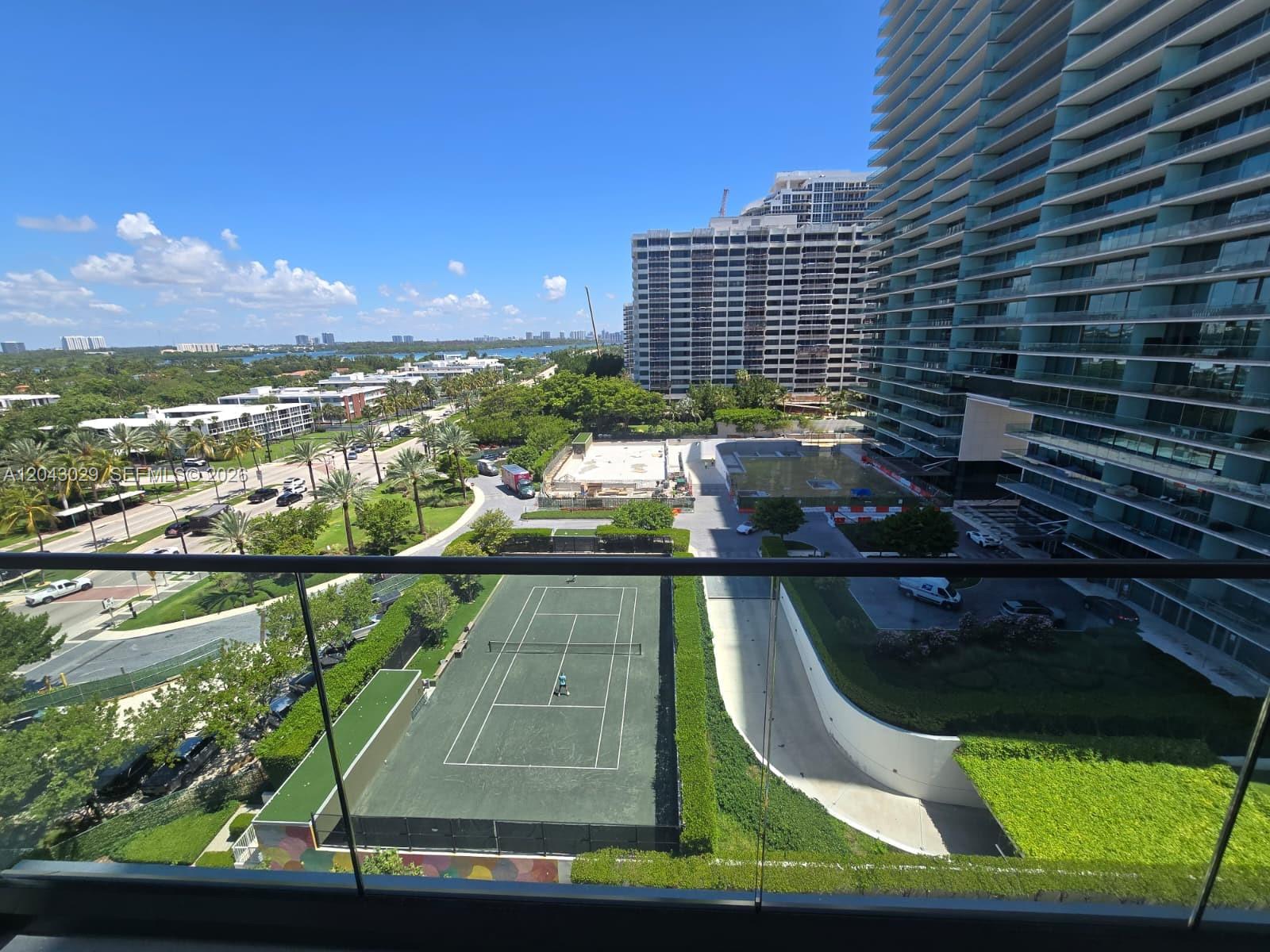 A high-angle view from a balcony overlooking a tennis court and nearby high-rise buildings — BAL HARBOUR, FL