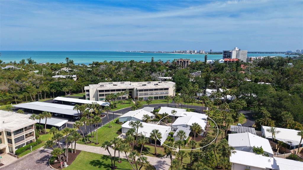 An aerial view shows a residential complex with white buildings, palm trees, and coastal water — 206 HOURGLASS WAY UNIT V10, SARASOTA, FL
