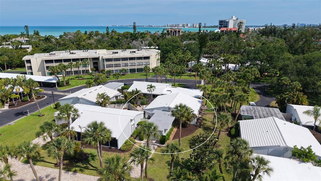 An aerial view shows a white-roofed residential building surrounded by palm trees and landscaping — 206 HOURGLASS WAY UNIT V10, SARASOTA, FL