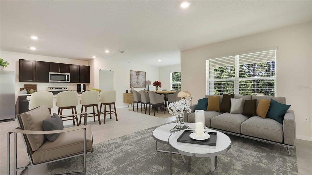 This open-concept living room features a kitchen with dark cabinetry and a dining area — 8609 TIDEWATER TRAIL AVENUE, TEMPLE TERRACE, FL