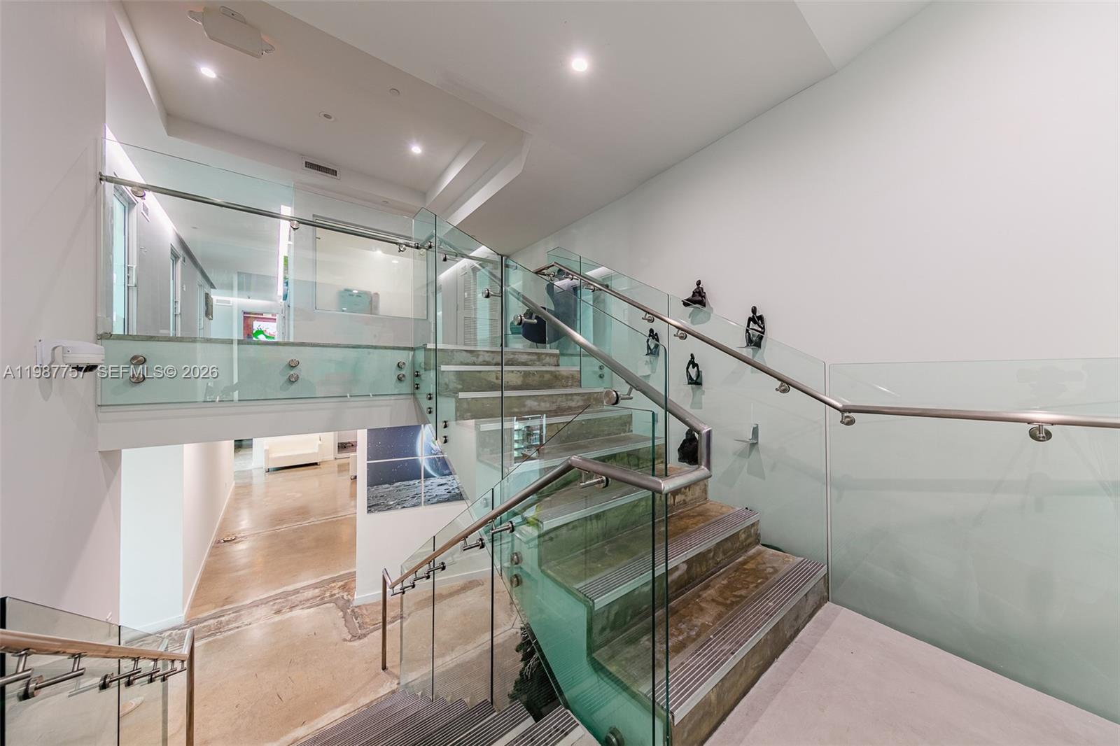 A modern staircase with concrete steps and glass railings connects two levels of a home — 350 S Miami Avenue, Miami FL 33130, MIAMI, FL