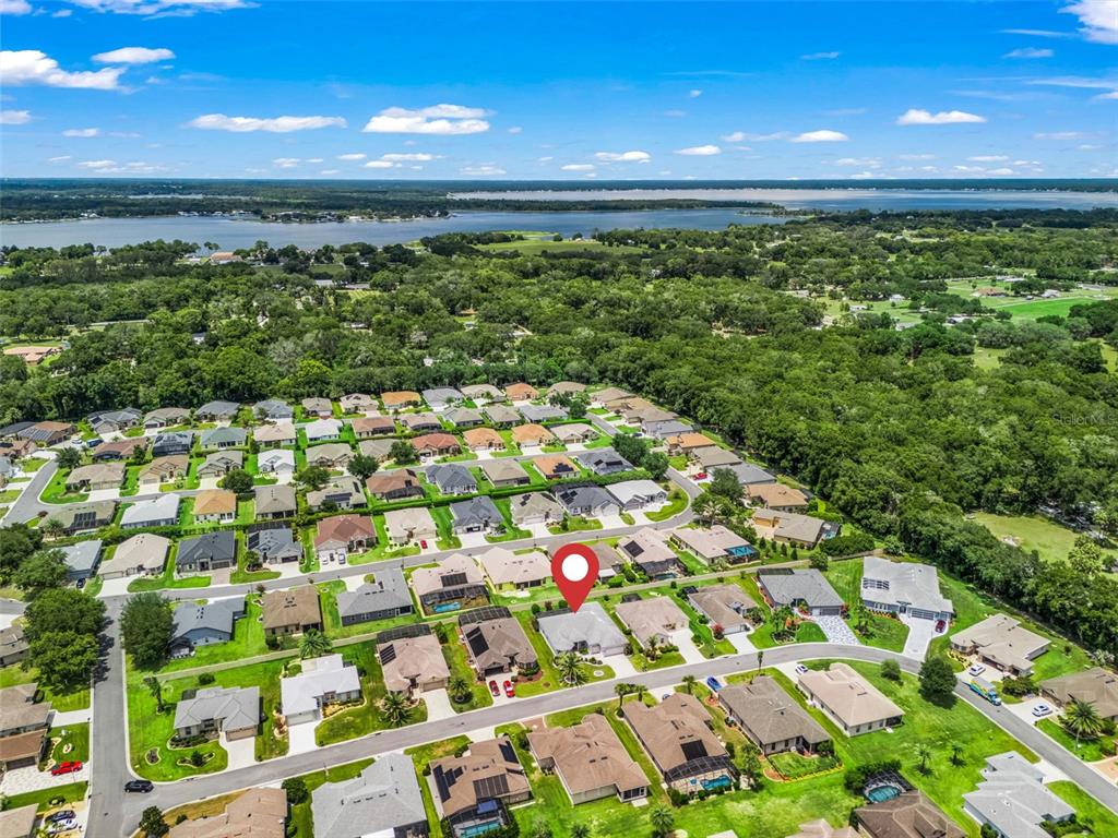 An aerial view shows a residential neighborhood with a marked house near a large lake — 16887 SE 110TH COURT ROAD, SUMMERFIELD, FL