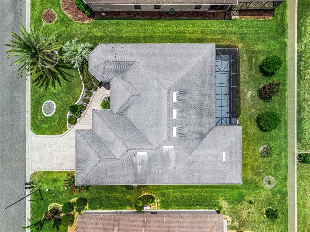 An aerial view shows a house with a gray shingled roof and a screened-in patio — 16887 SE 110TH COURT ROAD, SUMMERFIELD, FL