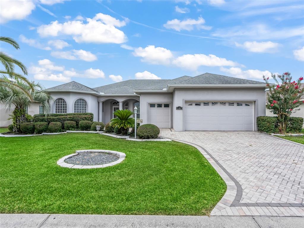 A single-story house with a gray exterior, a two-car garage, and a paved driveway — 16887 SE 110TH COURT ROAD, SUMMERFIELD, FL