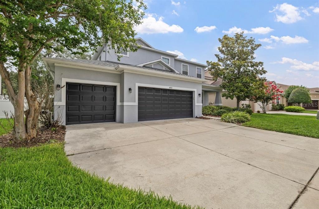 A two-story house with a gray exterior, a three-car garage, and a concrete driveway — 4400 WILDSTAR CIRCLE, WESLEY CHAPEL, FL