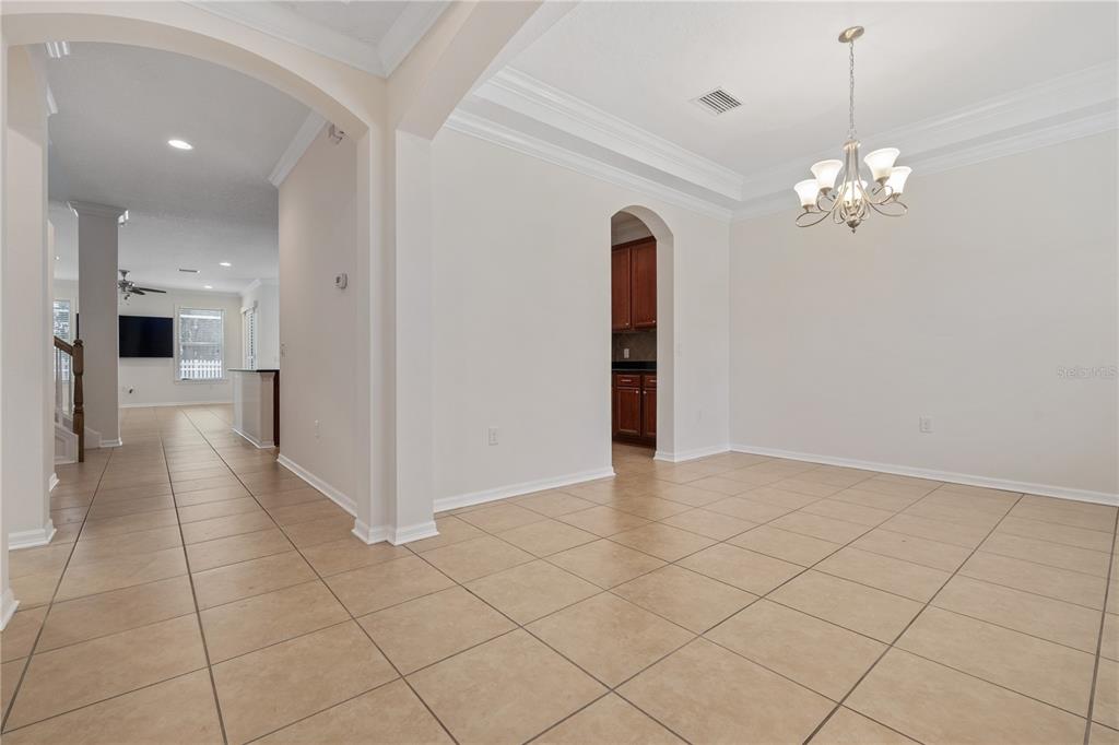 A dining area with tile flooring, a chandelier, and an arched doorway to the kitchen — 4400 WILDSTAR CIRCLE, WESLEY CHAPEL, FL