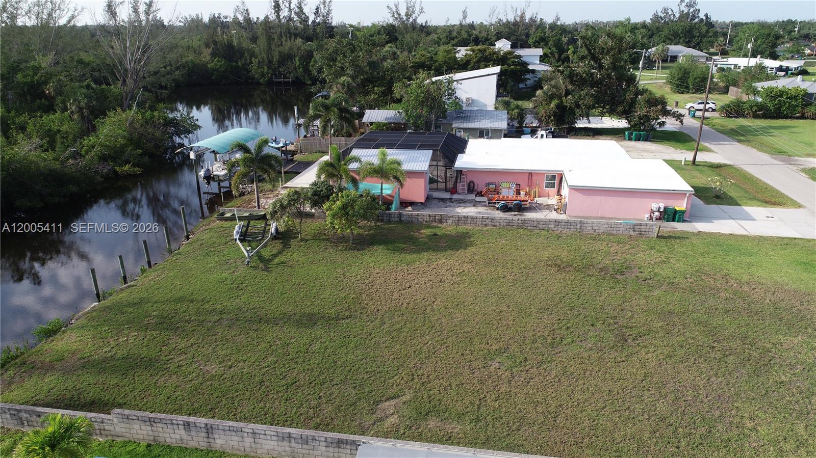 An aerial view shows a pink house with a screened patio next to a canal — 232 DARST AVE, Punta Gorda FL 33950, PUNTA GORDA, FL