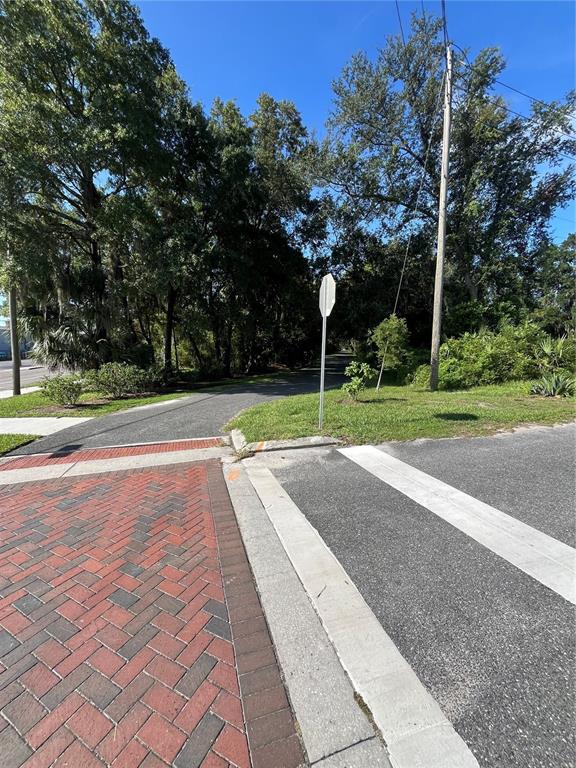 A paved path meets a brick crosswalk near a stop sign and wooded area — 214 NW 12TH AVENUE, GAINESVILLE, FL