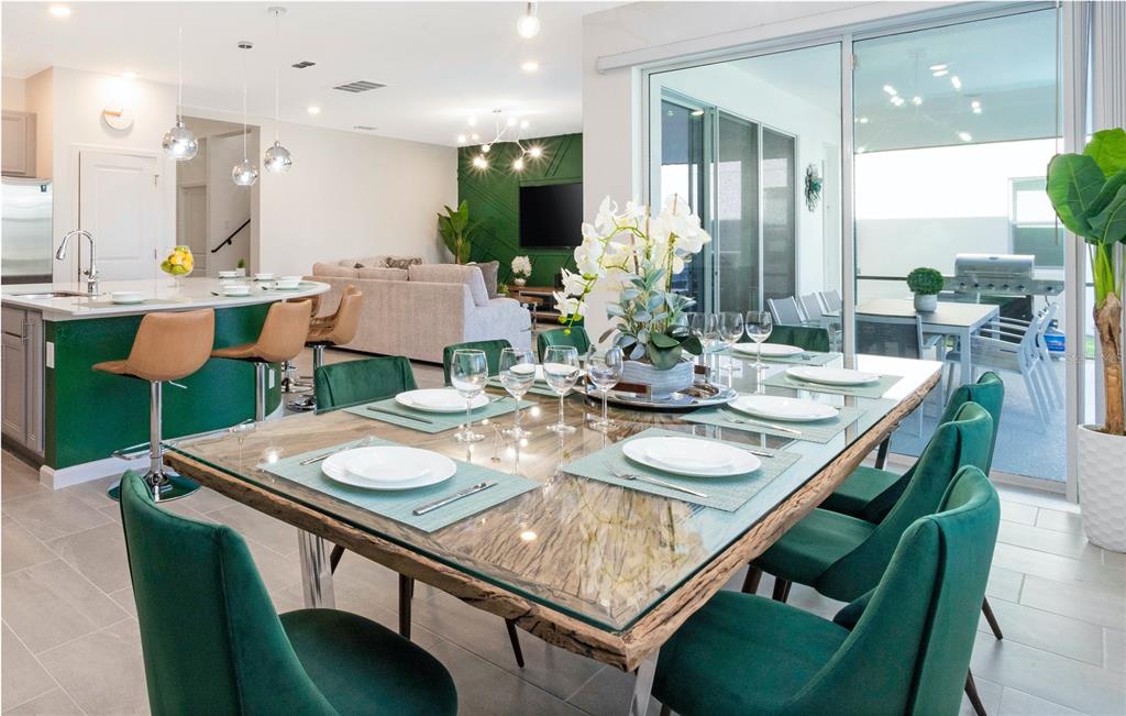 A dining room with a glass-topped wooden table, green velvet chairs, and an adjacent kitchen — 2569 SHANTI DRIVE, KISSIMMEE, FL
