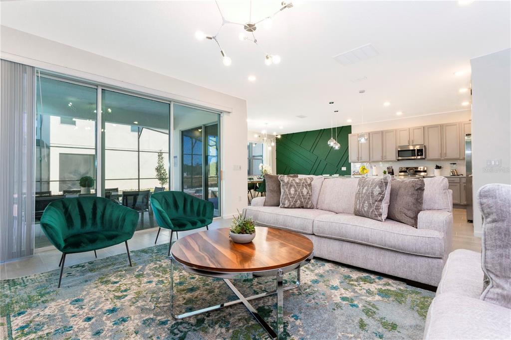 A living room features a light sofa, two green chairs, and a round wooden coffee table — 2569 SHANTI DRIVE, KISSIMMEE, FL