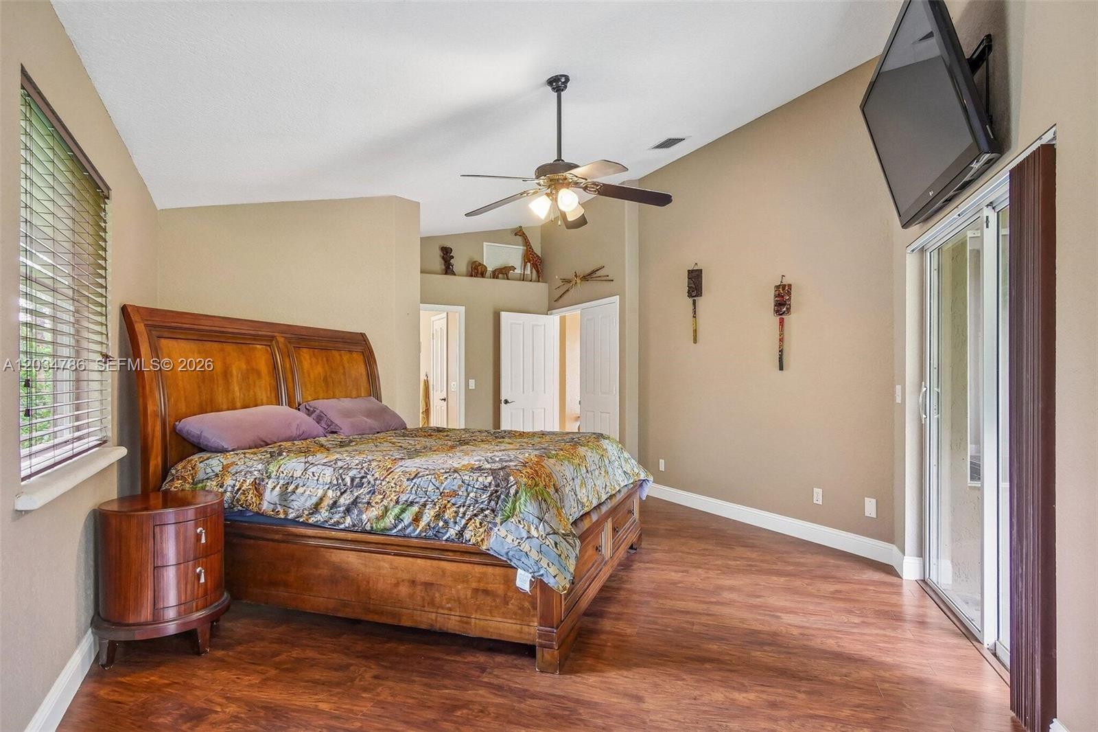 A bedroom features a wooden sleigh bed, vaulted ceiling, ceiling fan, and wood-look flooring — 14591 SW 23rd St, Davie FL 33325, DAVIE, FL