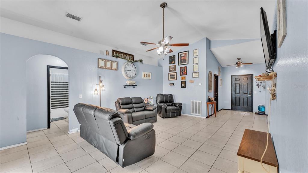 A living room with light blue walls, tile flooring, leather furniture, and a ceiling fan — 834 AUBURN PRESERVE BOULEVARD, AUBURNDALE, FL