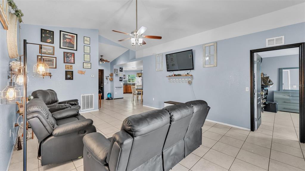 A living room features light blue walls, tile flooring, leather furniture, and a ceiling fan — 834 AUBURN PRESERVE BOULEVARD, AUBURNDALE, FL