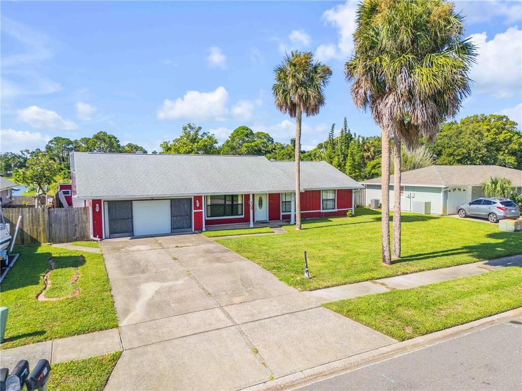A single-story red house with a gray roof and a concrete driveway sits outdoors — 709 TARRY TOWN TRAIL, PORT ORANGE, FL