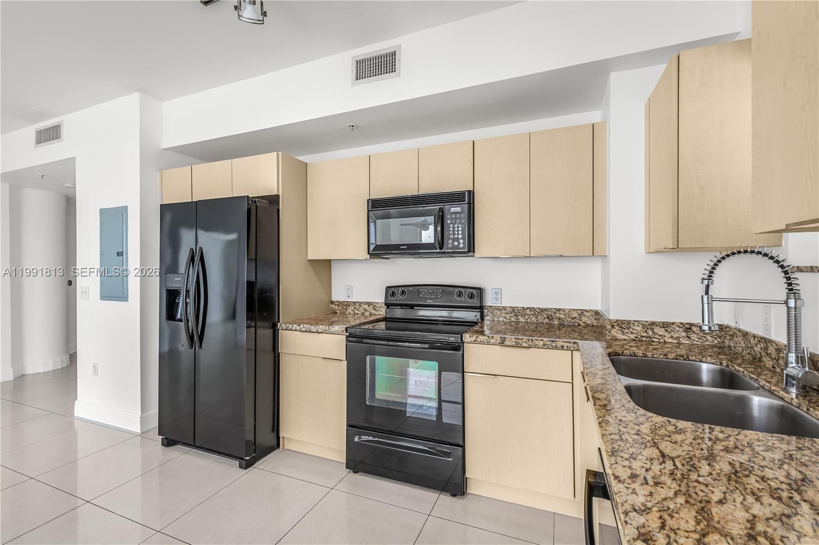 This open-concept kitchen and living area features light tile flooring and a ceiling fan — 3180 SW 22nd St # 601, Miami FL 33145, MIAMI, FL