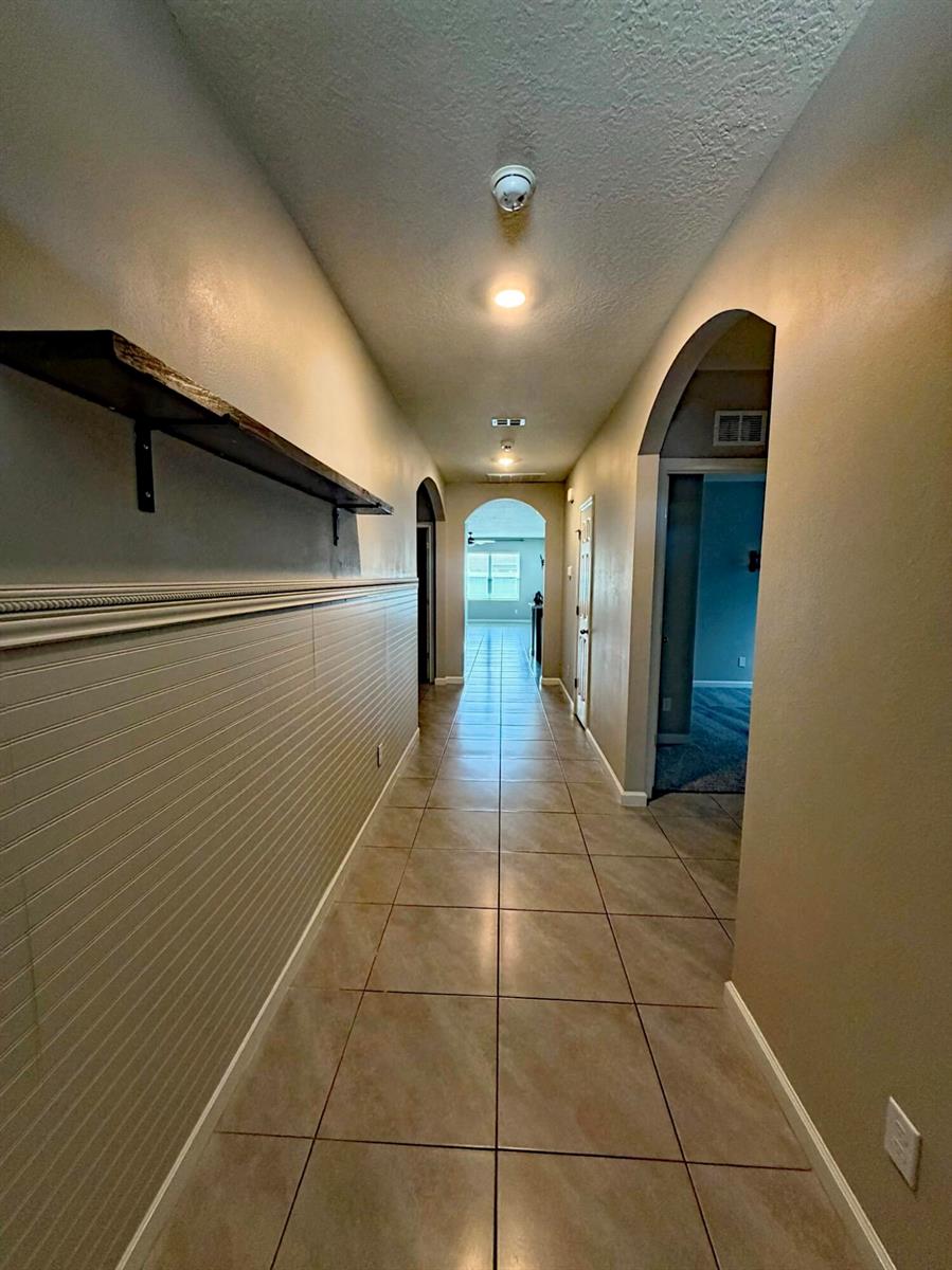 A hallway with tile flooring, beadboard wainscoting, and a floating wood shelf on the wall — 5306 Entertainment Way, Fort Pierce FL 34947, FORT PIERCE, FL
