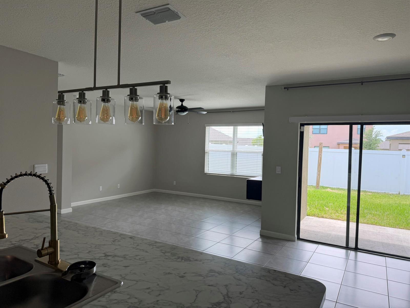 A kitchen island with a marble countertop overlooks an open living area with tile floors — 5306 Entertainment Way, Fort Pierce FL 34947, FORT PIERCE, FL