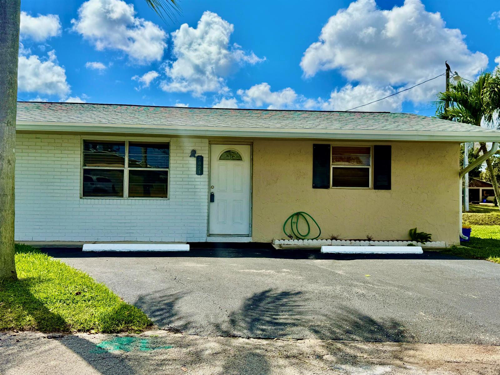 A single-story house with a white brick and tan stucco exterior faces a paved driveway — 2821 Duke Lane, Delray Beach FL 33445, DELRAY BEACH, FL