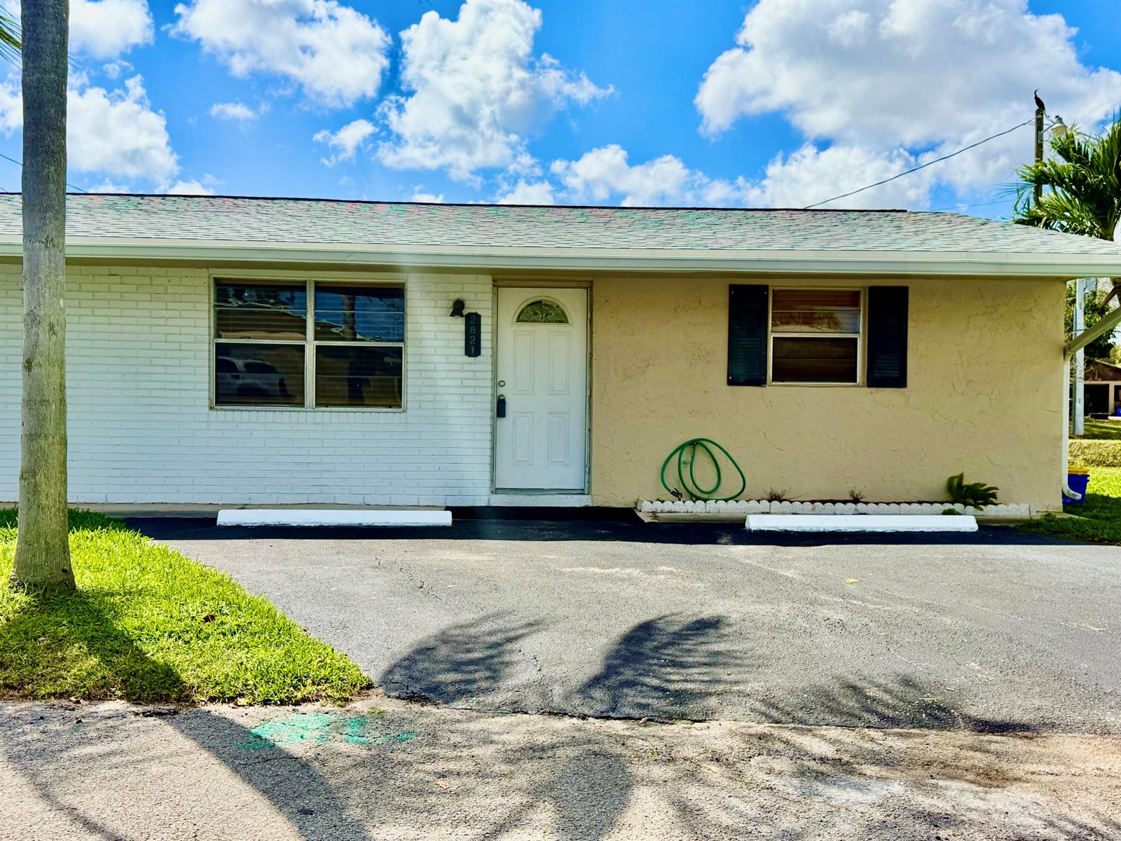 A single-story house with a white brick and tan stucco exterior under a blue sky — 2821 Duke Lane, Delray Beach FL 33445, DELRAY BEACH, FL