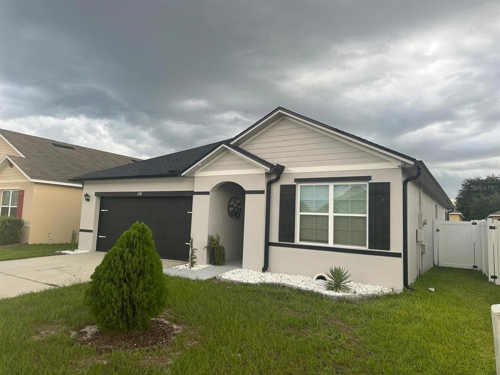 A single-story house with a beige stucco exterior, black shutters, and a two-car garage — 1199 SOPHIA BOULEVARD, WINTER HAVEN, FL