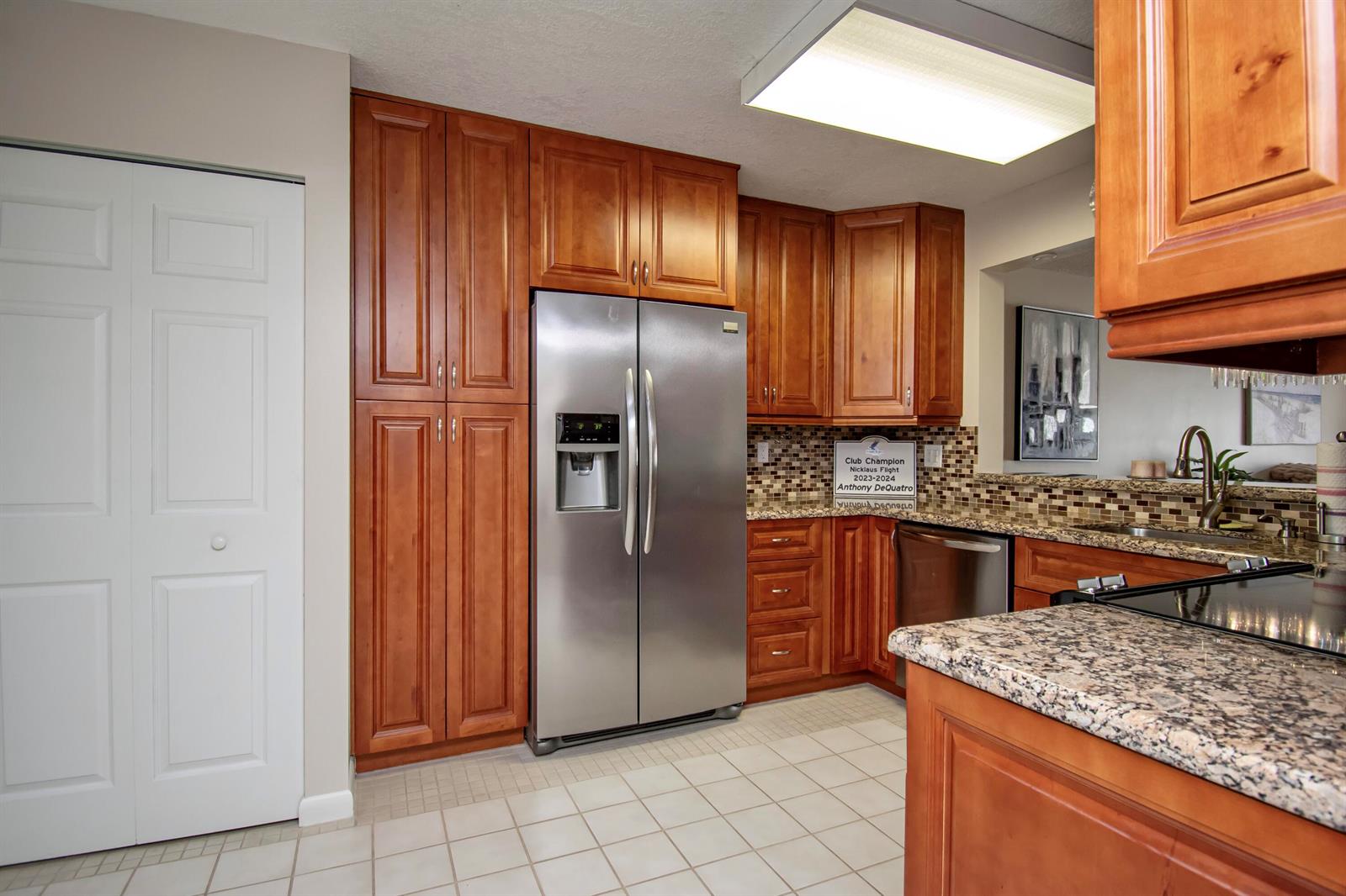 A kitchen features cherry wood cabinets, stainless steel appliances, granite countertops, and a tiled floor — 7286 Huntington Lane # 408, Delray Beach FL 33446, DELRAY BEACH, FL