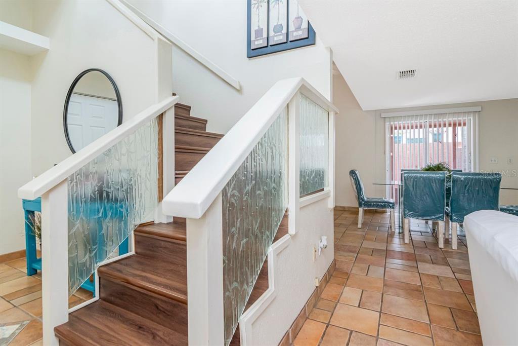 A staircase with wood treads and glass panels leads up from a tiled dining area — 10532 67TH AVENUE, SEMINOLE, FL