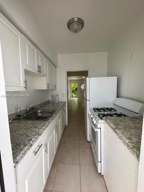 A galley kitchen features white cabinets, granite countertops, and a white stove and refrigerator — 30 S Shore Dr # 4, Miami Beach FL 33141, MIAMI BEACH, FL