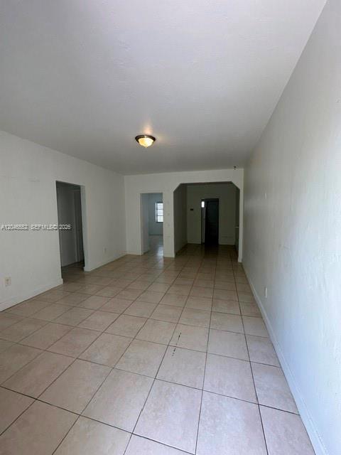 An empty room with beige tile flooring, white walls, and doorways leading to other rooms — 30 S Shore Dr # 4, Miami Beach FL 33141, MIAMI BEACH, FL