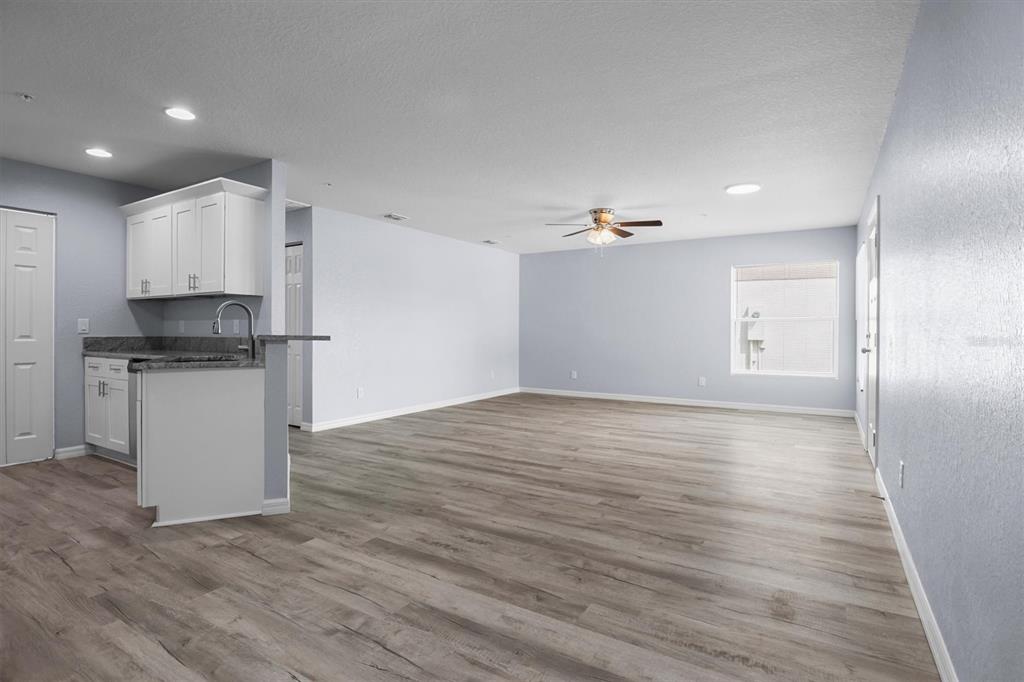 An open-concept living area features light gray walls, wood-look flooring, and a small kitchen corner — 4078 OAK LOOP, MULBERRY, FL