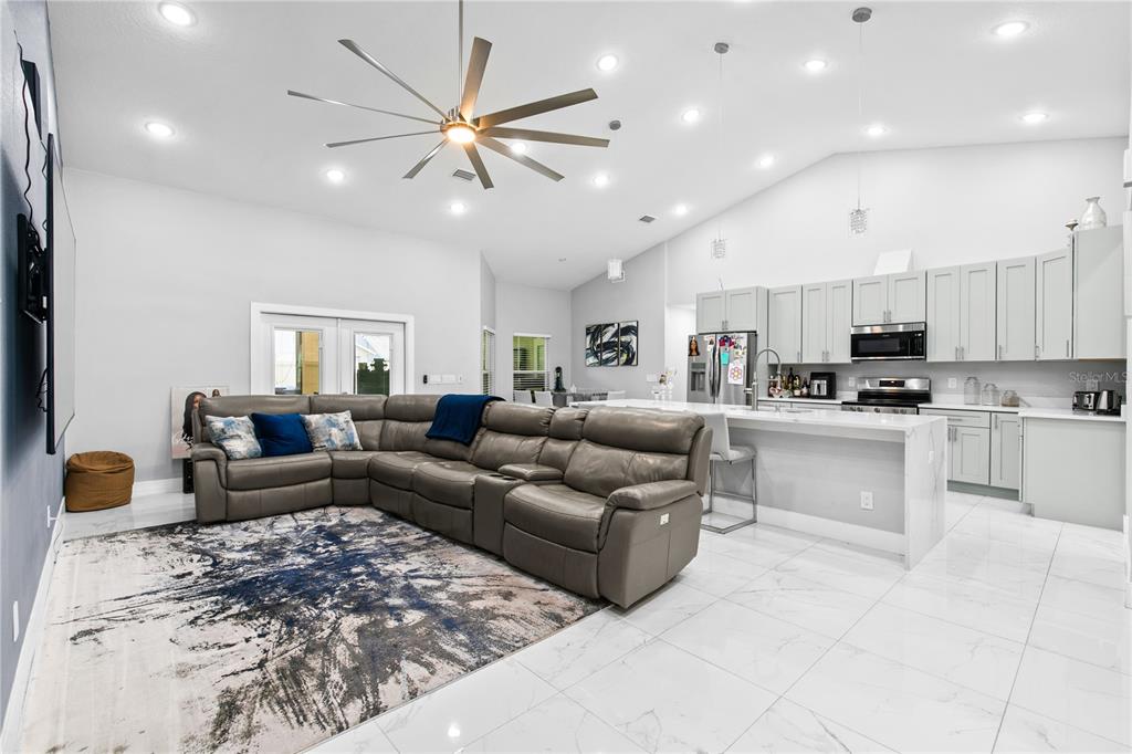 A modern open-concept living room and kitchen with a large sectional sofa and marble flooring — 14112 LORD BARCLAY DRIVE, ORLANDO, FL