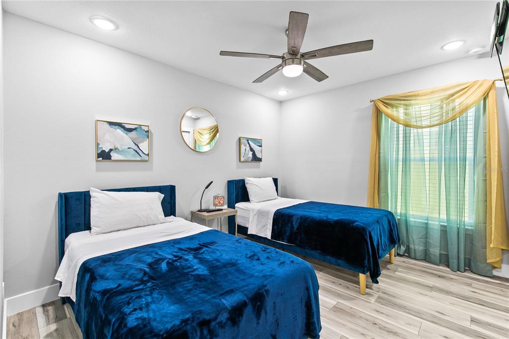 A bedroom features two twin beds with blue velvet frames and matching blankets — 14112 LORD BARCLAY DRIVE, ORLANDO, FL
