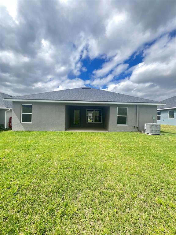 A single-story house with a gray stucco exterior, a two-car garage, and a front lawn — 13064 KENT BRADLEY STREET, DADE CITY, FL