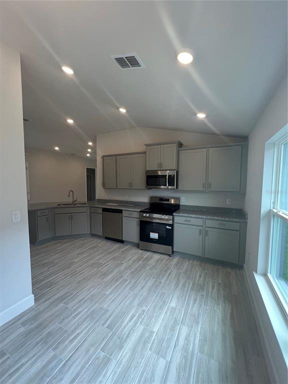 An open-concept living area features light wood-look tile flooring and a kitchen island — 13064 KENT BRADLEY STREET, DADE CITY, FL
