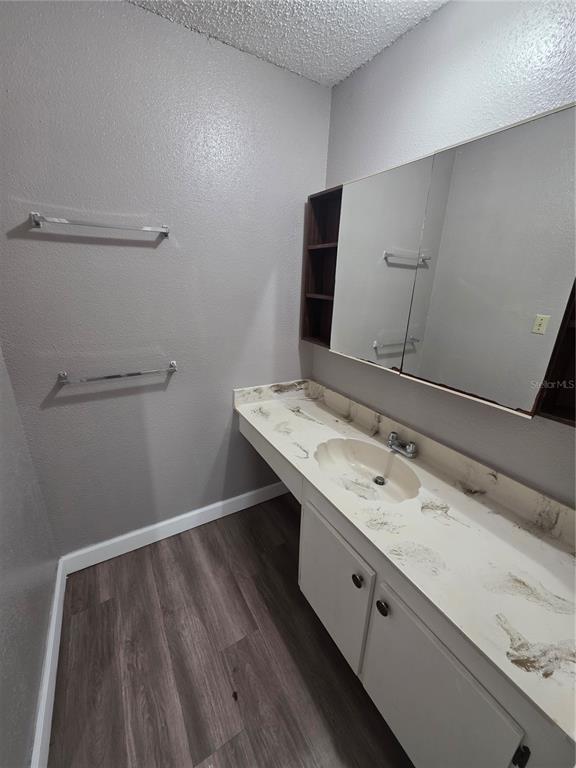 A bathroom features a vanity with a marble-look countertop, a medicine cabinet, and wood flooring — 2811 SW ARCHER ROAD UNIT R142, GAINESVILLE, FL