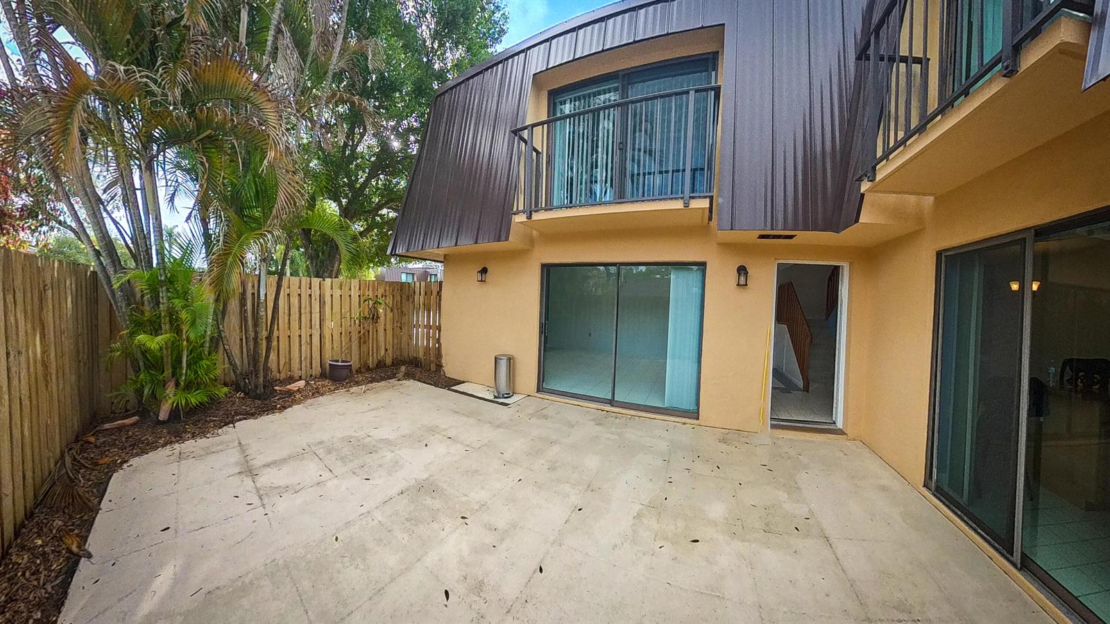 A concrete patio sits in front of a two-story building with sliding glass doors — 5646 SE Windsong Lane # 415, Stuart FL 34997, STUART, FL