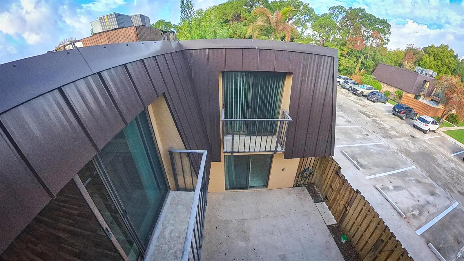 An elevated view of a building exterior featuring balconies, sliding glass doors, and a parking lot — 5646 SE Windsong Lane # 415, Stuart FL 34997, STUART, FL