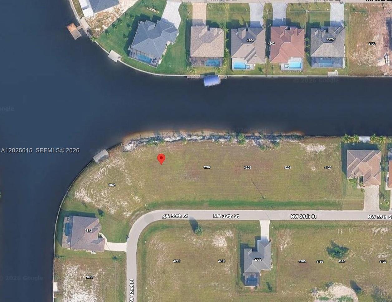 This is an aerial map showing a vacant waterfront lot and surrounding residential properties — CAPE CORAL, FL